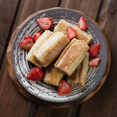 Wall Mural - Rolled pancakes with strawberries, above view, studio shot