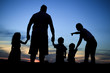 Silhouette of a young family with some childs standing