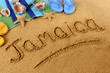 The word Jamaica written in sand on a beach with towel flip flops seashells Caribbean summer vacation holiday photo