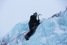 Ice Climber Ascending A Frozen Waterfall
