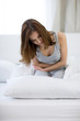 © Drobot Dean - Young woman in pain sitting on bed