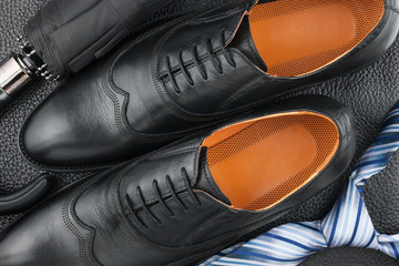 Classic men's shoes, tie, umbrella on the black leather