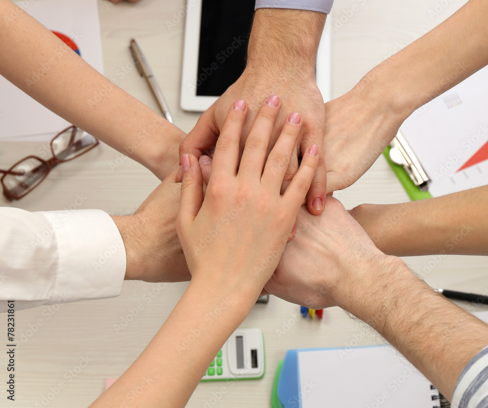 United hands of business team on workspace background top view