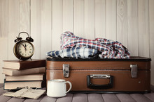 Vintage Suitcase With Clothes And Books On Wooden Background
