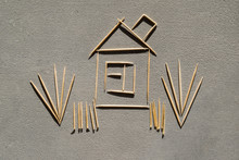 House And Grass Made Of Toothpicks On Concrete