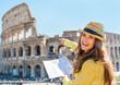 Happy young woman with map pointing on colosseum in rome, italy