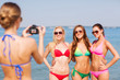 © Syda Productions - group of smiling women photographing on beach