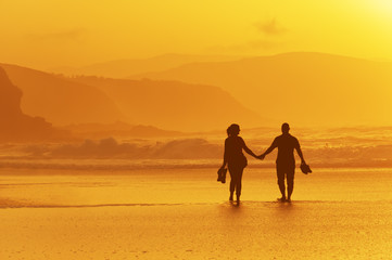 couple walking on beach at sunset