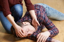 Woman Placing Man In Recovery Position After Accident