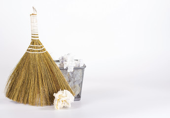 isolated besom and wastebasket full of waste paper