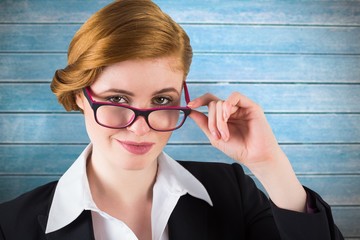 Poster - Composite image of redhead businesswoman touching her glasses