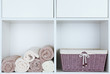 © Africa Studio - Rolled towels with wicker basket on shelf of rack background