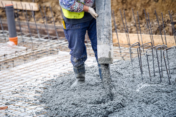 construction worker pouring cement or concrete with pump tube