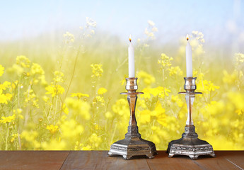 Wall Mural - two candlesticks with burning candles over wooden table and flow