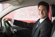 © WavebreakmediaMicro - Smiling businessman at the wheel sitting in a car for sale