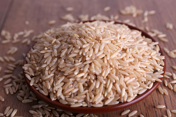 Poster - Brown rice on plate on wooden background