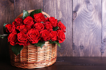 Wall Mural - Bouquet of red roses in basket on wooden background