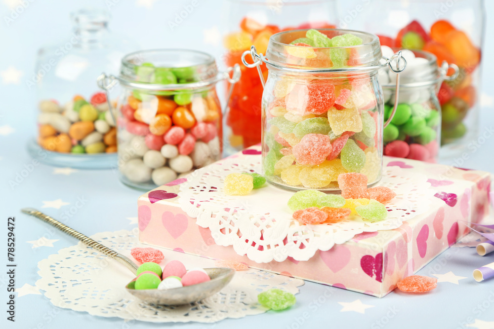 Multicolor candies in glass jars on colorful background