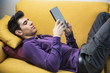 © theartofphoto - Attractive young man using tablet PC while laying on sofa