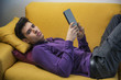 © theartofphoto - Attractive young man using tablet PC while laying on couch