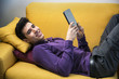 © theartofphoto - Attractive young man using tablet PC while laying on couch