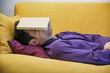© theartofphoto - Over-worked, tired young man at home sleeping under book