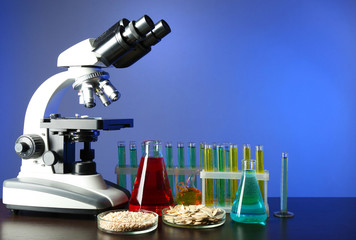 Wall Mural - Microscope, grains and test tubes on table, on color background