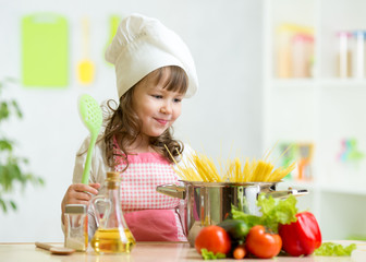 Wall Mural - Cook kid makes healthy vegetables meal in the kitchen