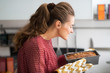 Young housewife smelling baking dish with bread