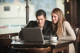 Fototapeta Tulipany - Couple at the bar using a laptop