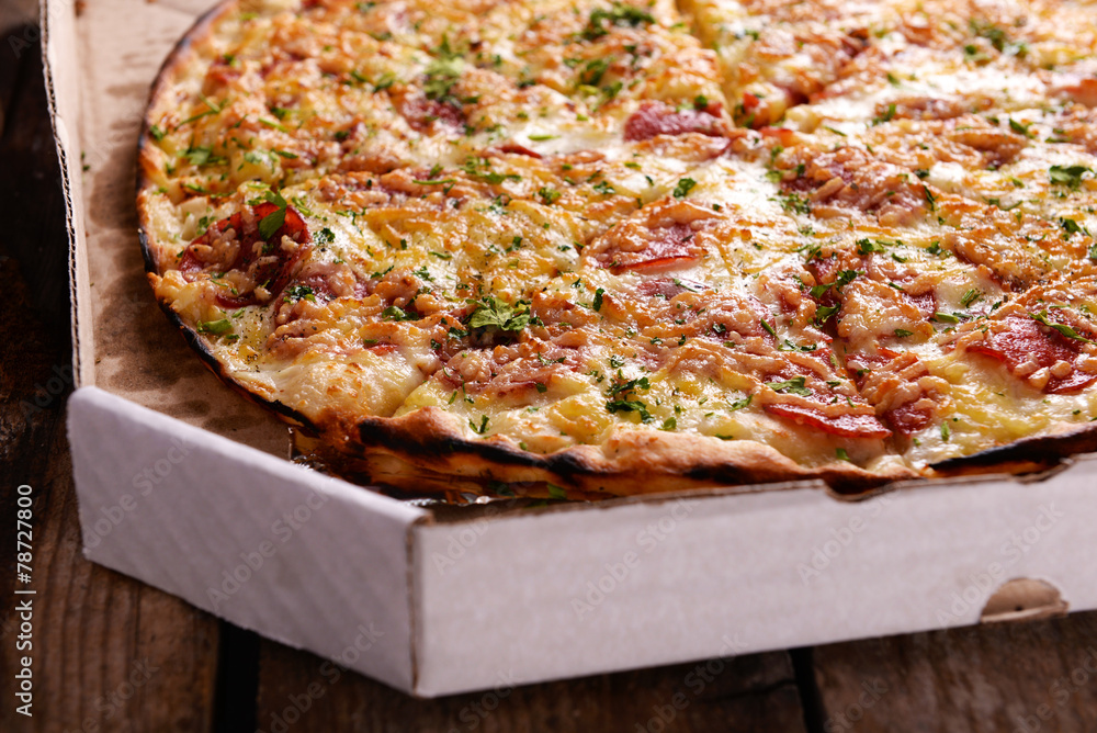 Tasty pizza in box on wooden background