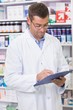 © WavebreakMediaMicro - Focused pharmacist writing on clipboard