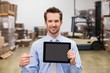 © WavebreakmediaMicro - Warehouse manager showing tablet pc smiling at camera