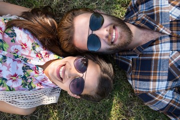 Young couple lying on grass smiling at camera