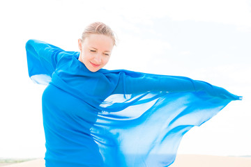 Wall Mural - Young woman with flying blue scarf