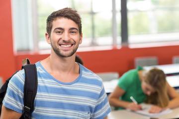 Happy male student standing in the classroom