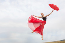 Young Woman Flying In The Sky With Red Umbrella