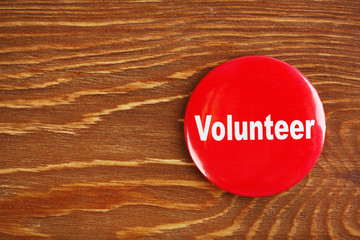 Wall Mural - Round volunteer button on wooden background