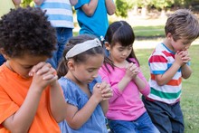 Children Saying Their Prayers In Park