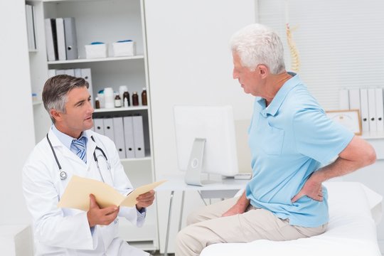 doctor discussing reports with patient suffering from backache