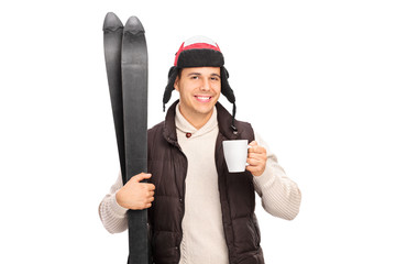 Poster - Young man holding skis and drinking hot tea