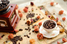 Coffee Beans And Dried Roses Scattered Upon The Old Map