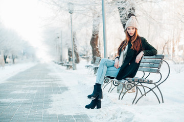 Wall Mural - young woman in winter park sitting on the bench