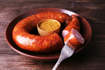 Canvas Print - Smoked sausage with mustard on plate on wooden table background