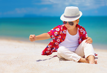 Wall Mural - stylish kid, boy playing with sand on summer beach