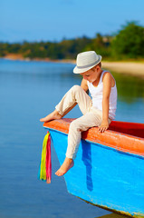 Wall Mural - cute kid, boy sitting on the bow of a boat