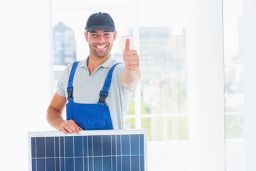 Poster - Workman with solar panel gesturing thumbs up in bright office