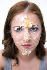 Wall Mural - Serious woman sitting at the table with cake at her face