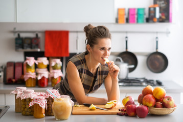 Wall Mural - Young housewife standing near jars with fruits jam 