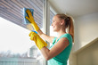 © Syda Productions - happy woman in gloves cleaning window with rag